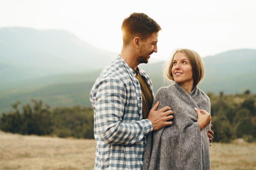 Happy loving couple hiking and hugging in mountains