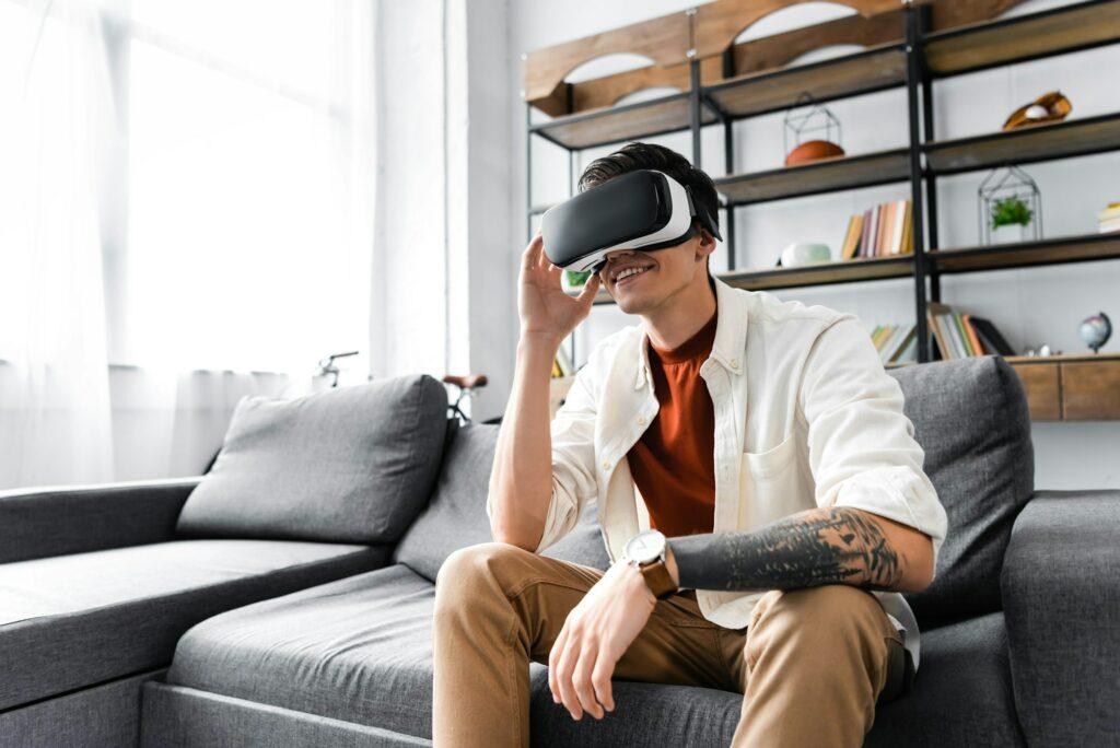 man with virtual reality headset sitting on sofa in apartment