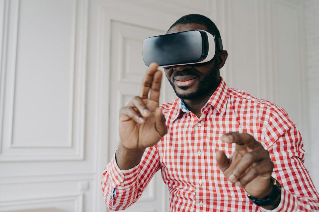 Young african man wearing VR glasses enjoying gaming experience at home